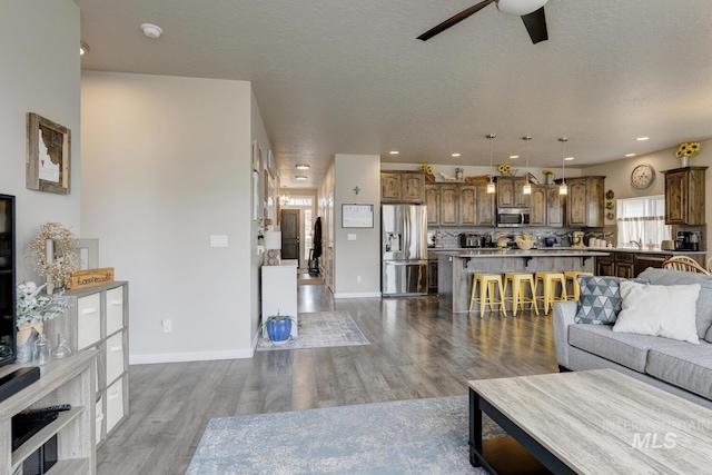 living area featuring recessed lighting, baseboards, a ceiling fan, and wood finished floors