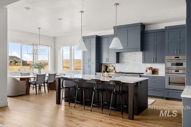 kitchen with appliances with stainless steel finishes, decorative backsplash, custom range hood, and a wealth of natural light