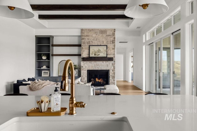 living room with built in shelves, a fireplace, and sink