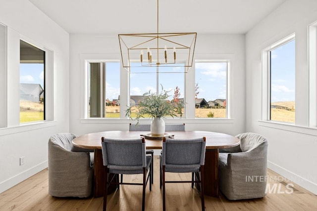 dining room featuring a wealth of natural light, light wood-type flooring, and a notable chandelier