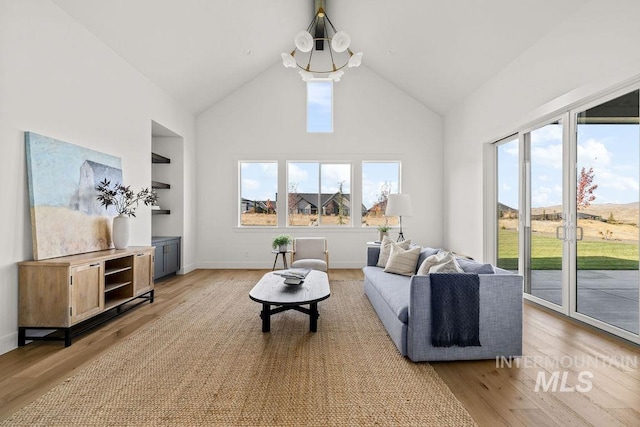 living room with a notable chandelier, light wood-type flooring, and lofted ceiling