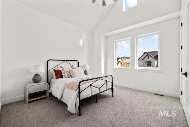 carpeted bedroom with high vaulted ceiling