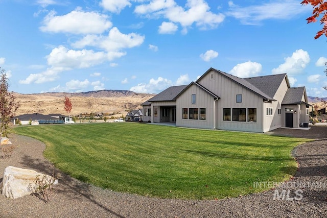 back of house with a mountain view and a yard