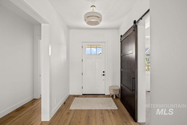 entrance foyer featuring a barn door, a wealth of natural light, and light hardwood / wood-style flooring