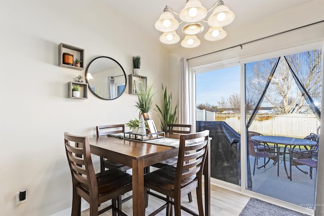 dining area with an inviting chandelier, light hardwood / wood-style flooring, and lofted ceiling