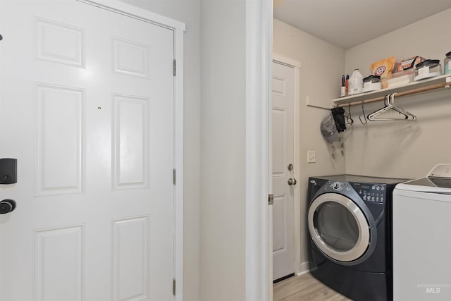 washroom with washer and clothes dryer and light wood-type flooring