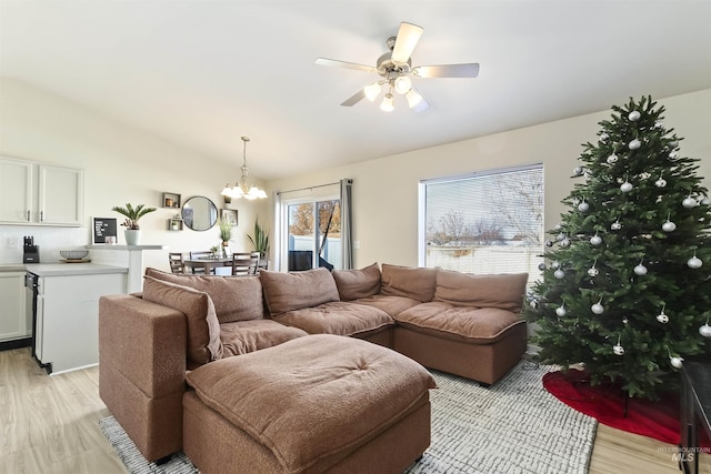 living room featuring ceiling fan with notable chandelier and light hardwood / wood-style flooring