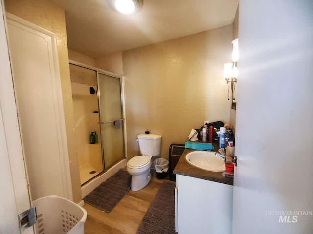 bathroom featuring vanity, wood-type flooring, toilet, and walk in shower