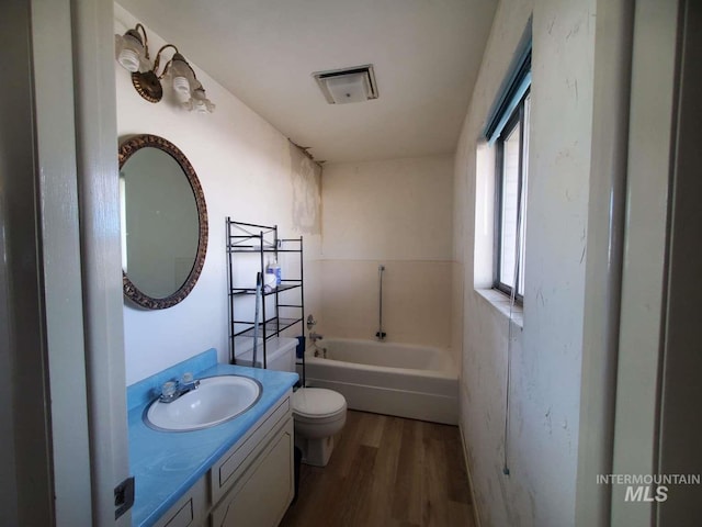 bathroom featuring wood-type flooring, a washtub, vanity, and toilet