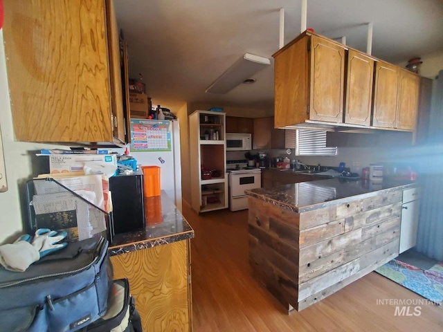 kitchen with sink, white appliances, and wood-type flooring