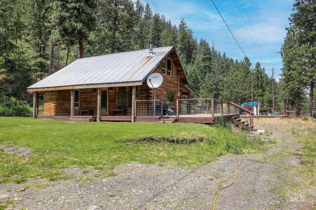 5650 Pines Rd, New Meadows, ID 83654 - view of front of house with a porch, a metal roof, a front lawn, log exterior, and a forest view