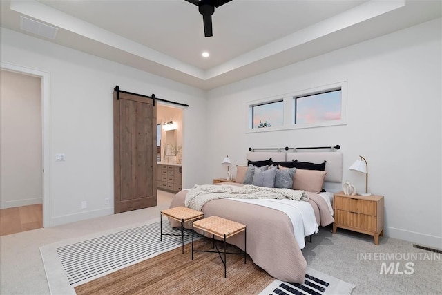 9989 W Bouvardia St, Star, ID 83699 - bedroom featuring a barn door, a tray ceiling, light colored carpet, baseboards, and connected bathroom