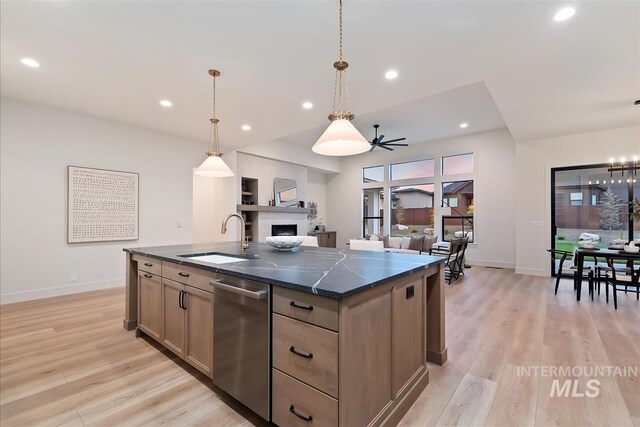 9989 W Bouvardia St, Star, ID 83699 - kitchen featuring a sink, stainless steel dishwasher, dark countertops, a kitchen island with sink, and light wood-style floors