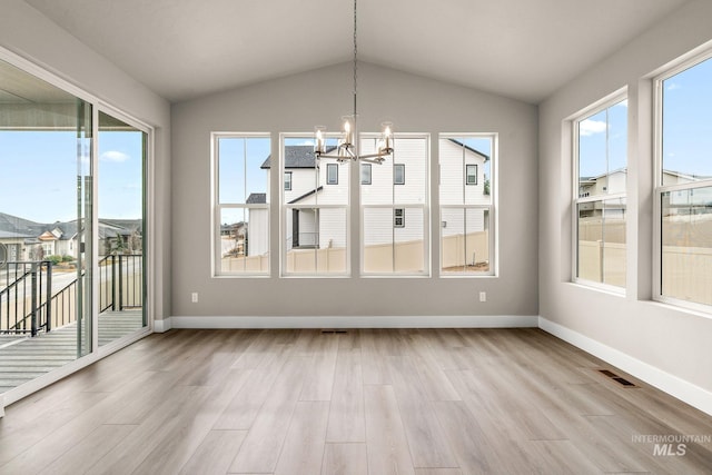 unfurnished dining area featuring an inviting chandelier, vaulted ceiling, light wood-style flooring, and baseboards