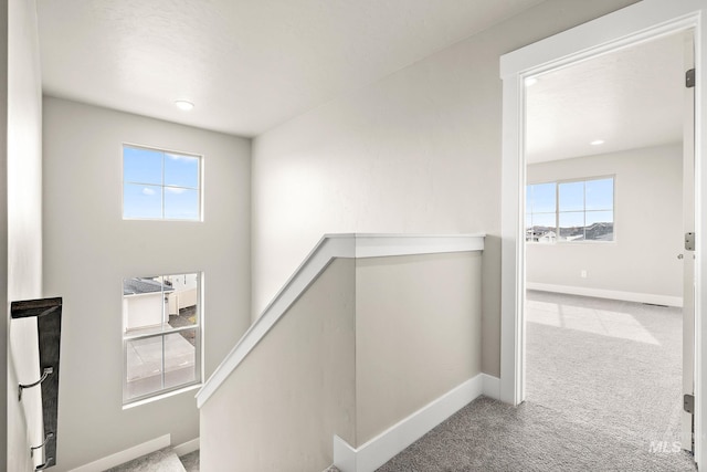 hall with baseboards, an upstairs landing, and carpet flooring