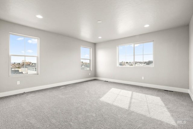 spare room featuring carpet flooring, recessed lighting, baseboards, and visible vents