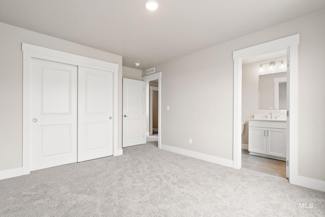 unfurnished bedroom with visible vents, ensuite bathroom, a sink, a closet, and light colored carpet