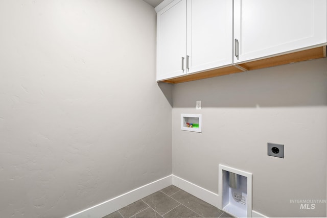 clothes washing area featuring baseboards, dark tile patterned floors, washer hookup, cabinet space, and electric dryer hookup