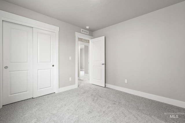 unfurnished bedroom featuring carpet flooring, baseboards, visible vents, and a closet