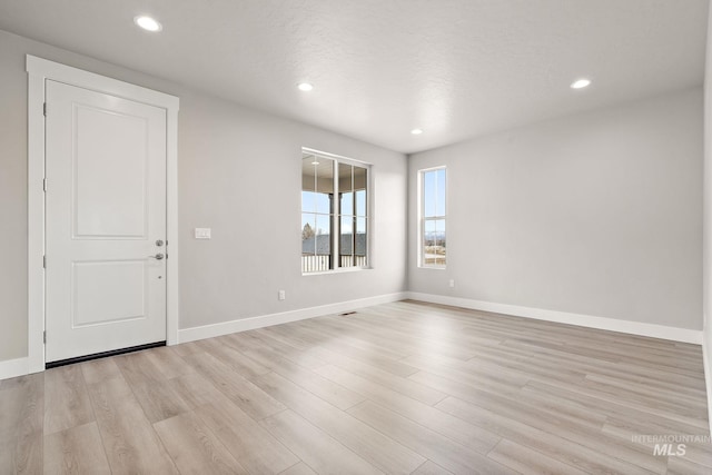 spare room featuring recessed lighting, baseboards, and light wood finished floors