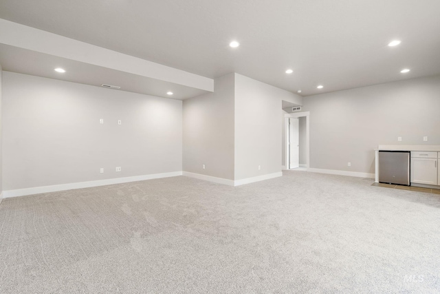 below grade area featuring light colored carpet, fridge, recessed lighting, and baseboards