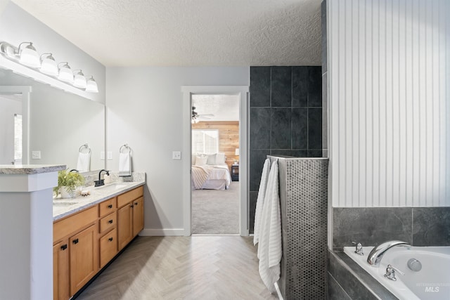 bathroom with double vanity, ensuite bathroom, a sink, a textured ceiling, and a bath