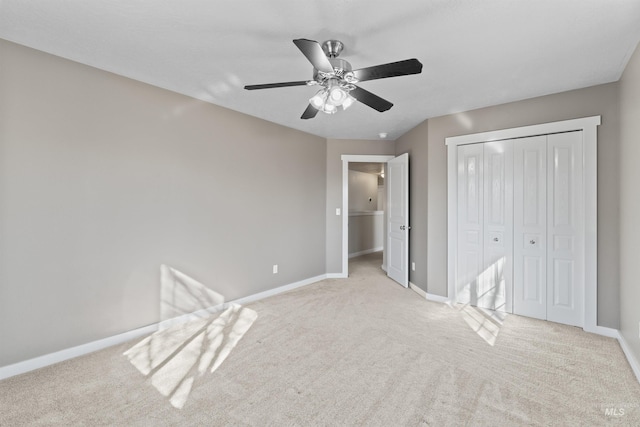 unfurnished bedroom featuring a closet, light colored carpet, ceiling fan, and baseboards