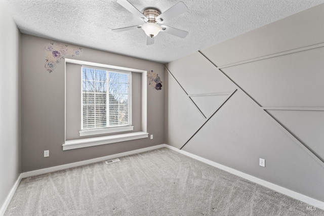 carpeted empty room with a ceiling fan, visible vents, a textured ceiling, and baseboards