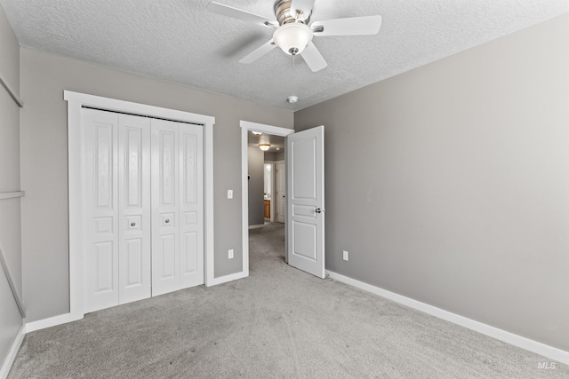 unfurnished bedroom with carpet, a closet, a textured ceiling, and baseboards