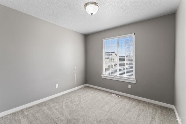 carpeted empty room featuring baseboards, visible vents, and a textured ceiling