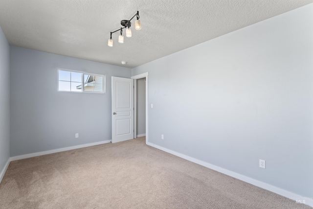 carpeted spare room with a textured ceiling and baseboards