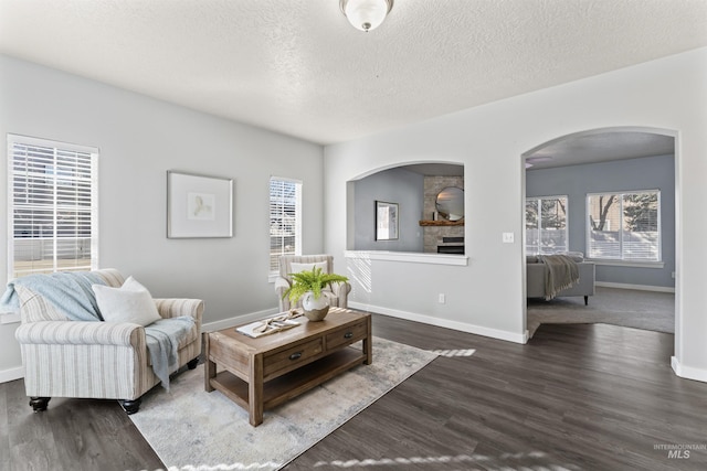 living room with a textured ceiling, baseboards, and dark wood-style flooring