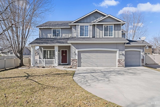 view of front of house with a porch, fence, concrete driveway, board and batten siding, and a front yard