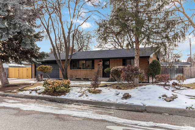 ranch-style home featuring fence, brick siding, and an attached garage