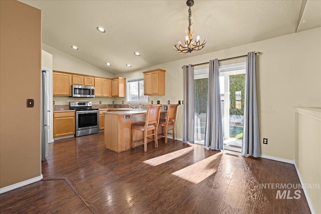 kitchen with stainless steel appliances, a healthy amount of sunlight, a breakfast bar area, a center island, and lofted ceiling