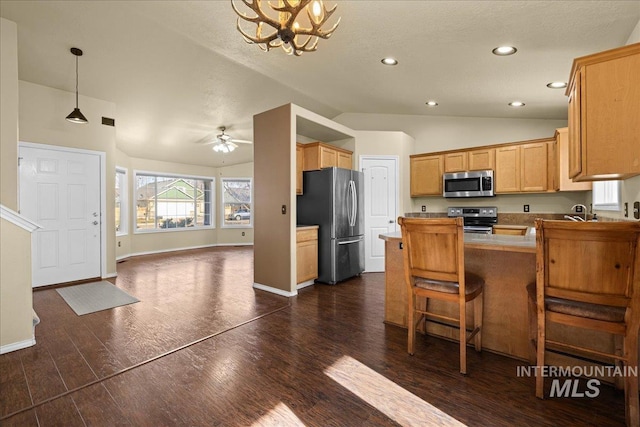 kitchen featuring stainless steel appliances, kitchen peninsula, lofted ceiling, a breakfast bar, and ceiling fan with notable chandelier