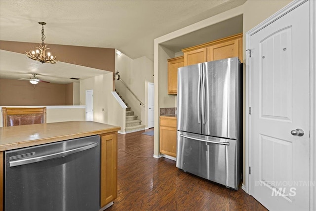 kitchen featuring hanging light fixtures, dark hardwood / wood-style flooring, vaulted ceiling, ceiling fan with notable chandelier, and appliances with stainless steel finishes