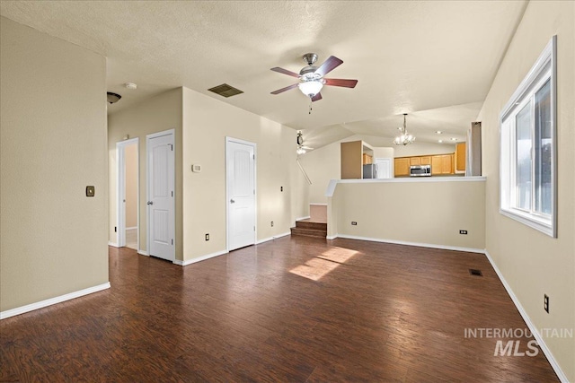 unfurnished living room with ceiling fan with notable chandelier, dark hardwood / wood-style floors, a textured ceiling, and vaulted ceiling