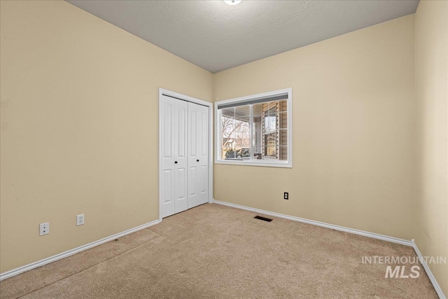 unfurnished bedroom featuring light carpet and a closet