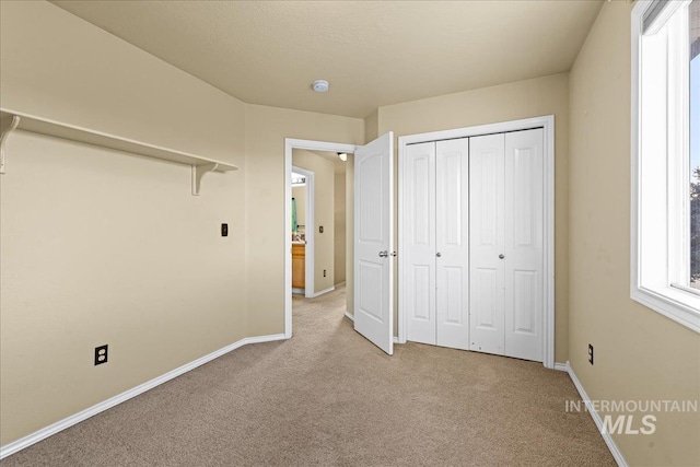 unfurnished bedroom featuring light colored carpet and a closet