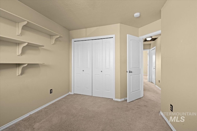 unfurnished bedroom with light carpet, a closet, and a textured ceiling