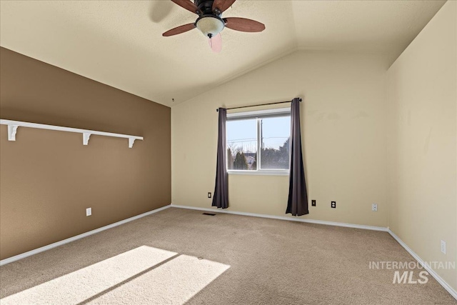 carpeted spare room with ceiling fan and vaulted ceiling