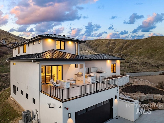3149 N Lancaster Pl, Boise, ID 83702 - back of property at dusk featuring a standing seam roof, metal roof, central AC unit, stucco siding, and an attached garage