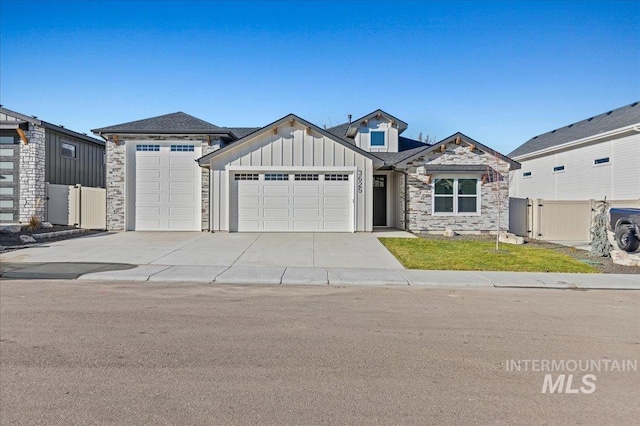 view of front facade with a garage, concrete driveway, stone siding, fence, and board and batten siding