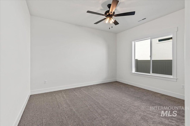 empty room with carpet, visible vents, ceiling fan, and baseboards