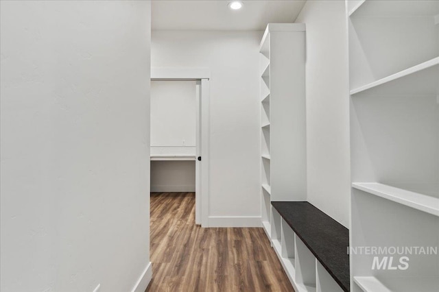 walk in closet with dark wood-style flooring