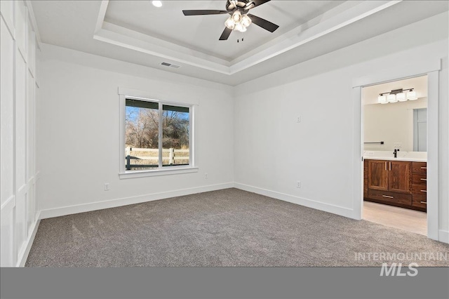 unfurnished bedroom with light carpet, a raised ceiling, visible vents, and baseboards