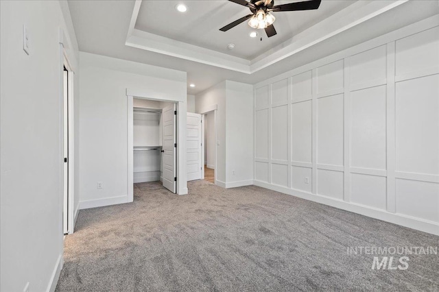 unfurnished bedroom with recessed lighting, a raised ceiling, light colored carpet, and baseboards