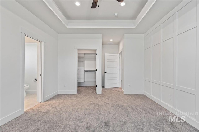 unfurnished bedroom with light carpet, recessed lighting, a raised ceiling, and baseboards