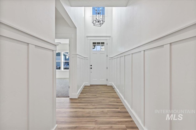 entrance foyer with a wainscoted wall, a notable chandelier, a decorative wall, and wood finished floors